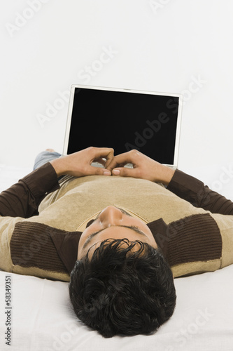 Man lying on the bed with a laptop
