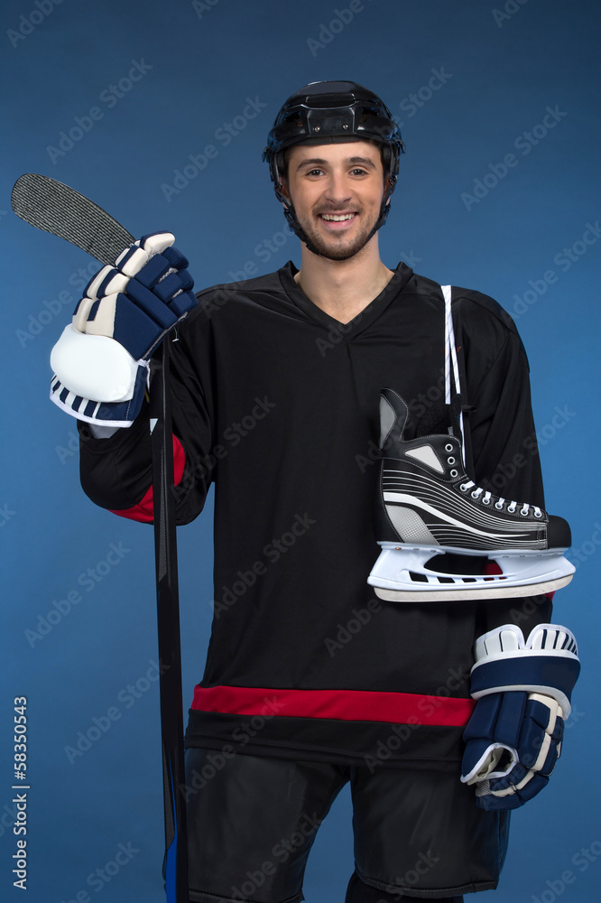 Naklejka premium Smiling hockey player with skates over shoulder