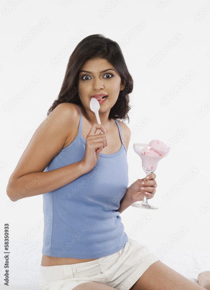 Portrait of a woman licking a spoon of ice cream