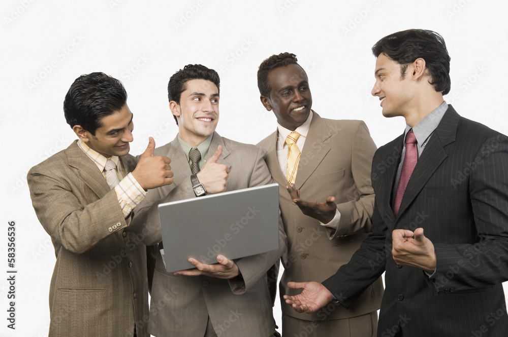 Four businessmen smiling in front of a laptop Four businessmen smiling in front of a laptop