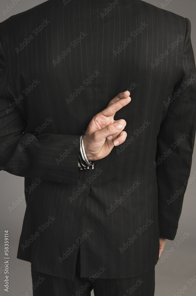 Fototapeta premium Businessman with fingers crossed behind his back