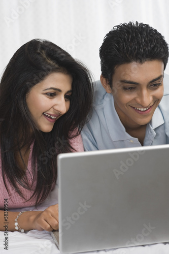 Couple using a laptop on the bed