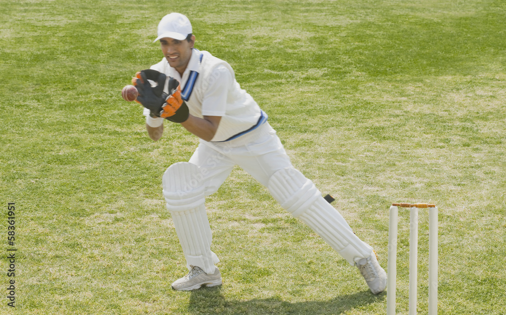 Obraz premium Cricket wicketkeeper catching a ball behind stumps
