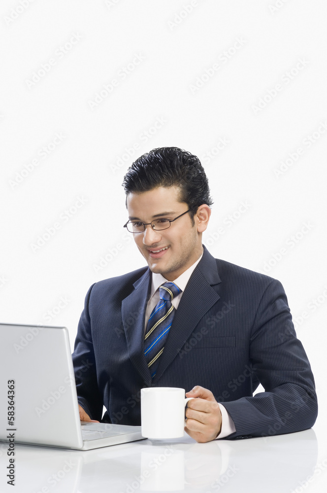 Businessman drinking coffee while working on a laptop Businessman drinking coffee while working on a laptop