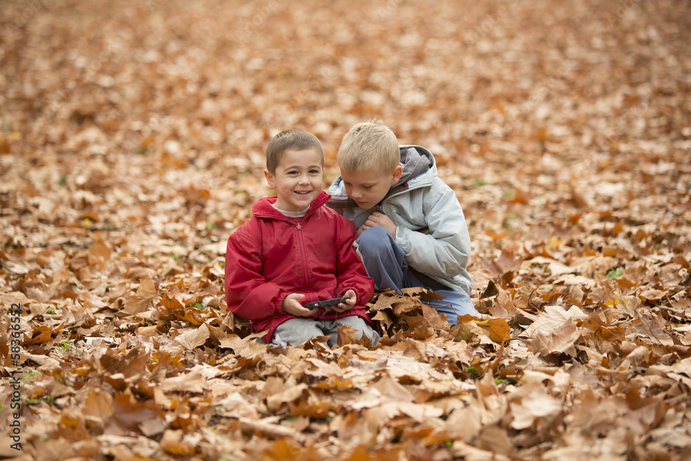 Two brothers play together, sitting on ground, outdoor Two brothers play together, sitting on ground, outdoor