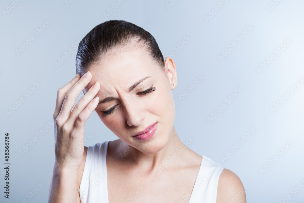 Woman having a headache holding her forehead in pain Woman having a headache holding her forehead in pain
