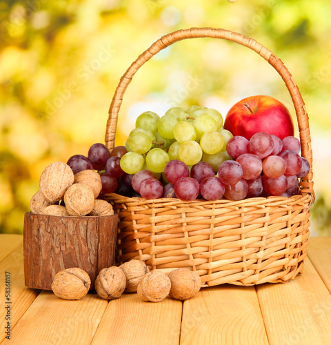 Grape in basket with nuts on wooden table