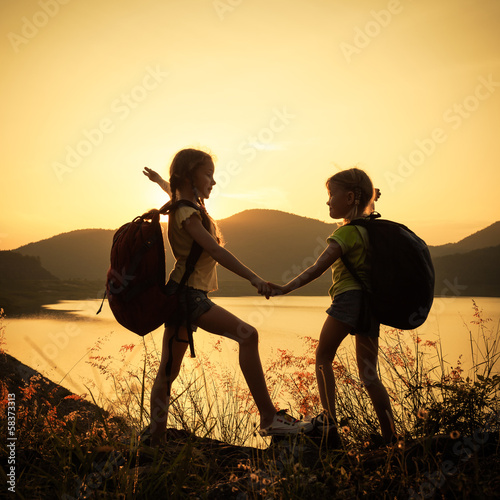 Photography two little girls watching the sunset on the lake