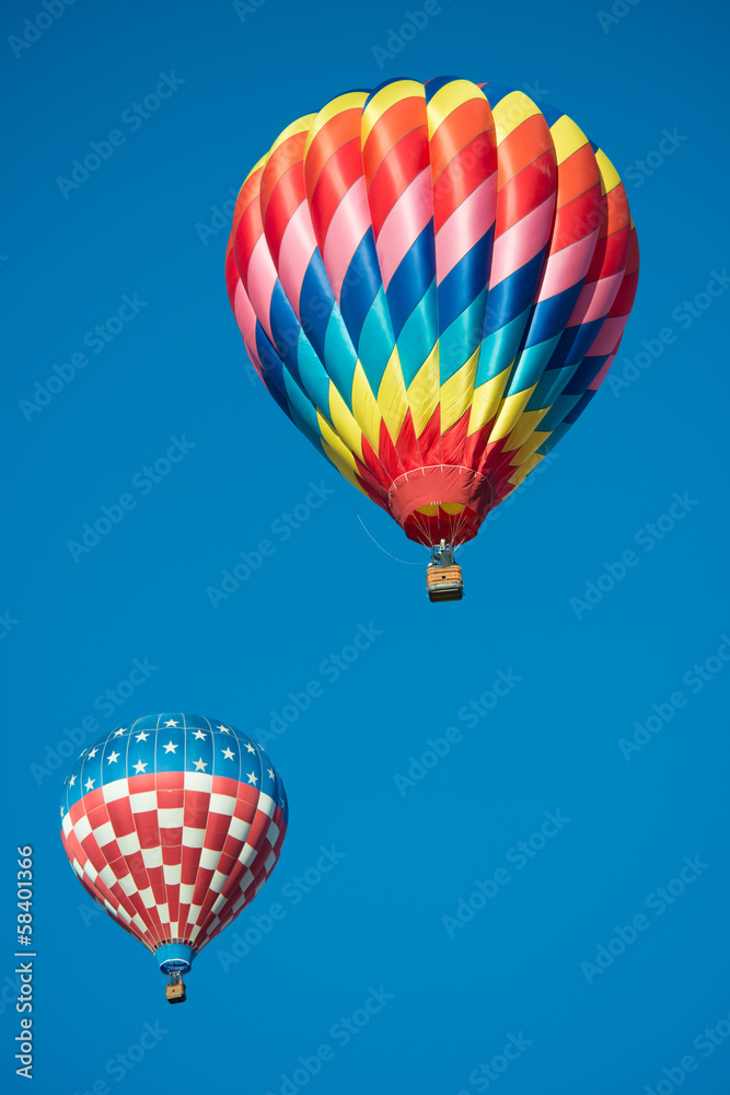 Obraz premium Two brightly colored hot air balloons with a sky blue background