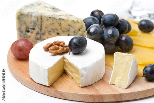 Assorted cheeses and grapes on a wooden board, isolated