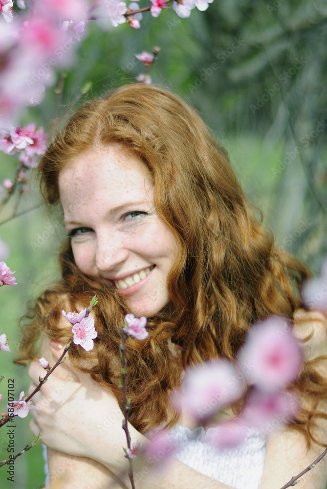 Fototapeta premium beautiful red-haired girl among the flowering trees