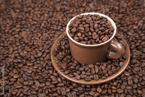 Brown cup with coffee on coffee beans