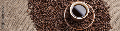 Brown cup with coffee on coffee beans