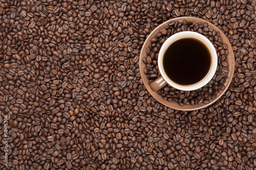 Brown cup with coffee on coffee beans