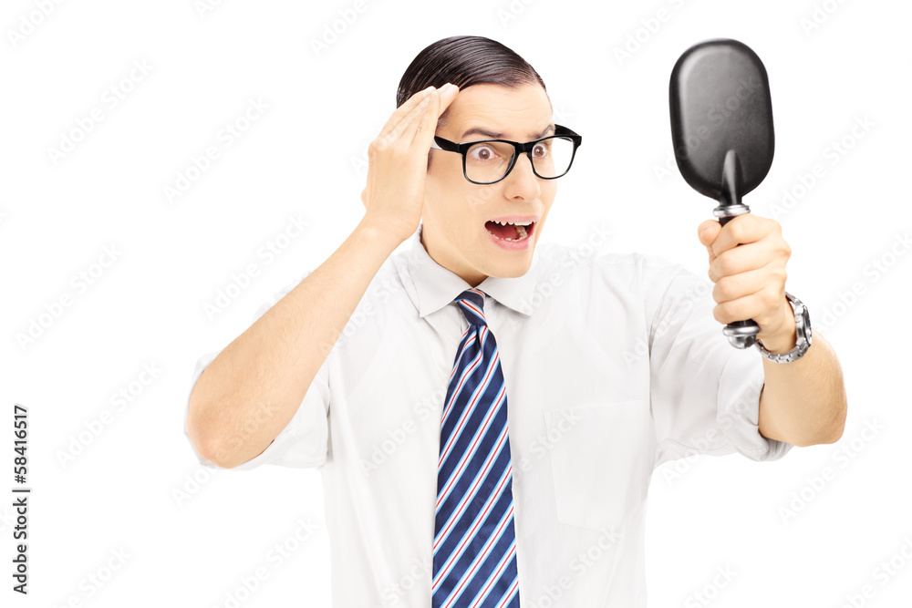 Young worried man checking for thinning hair in the mirror Young worried man checking for thinning hair in the mirror