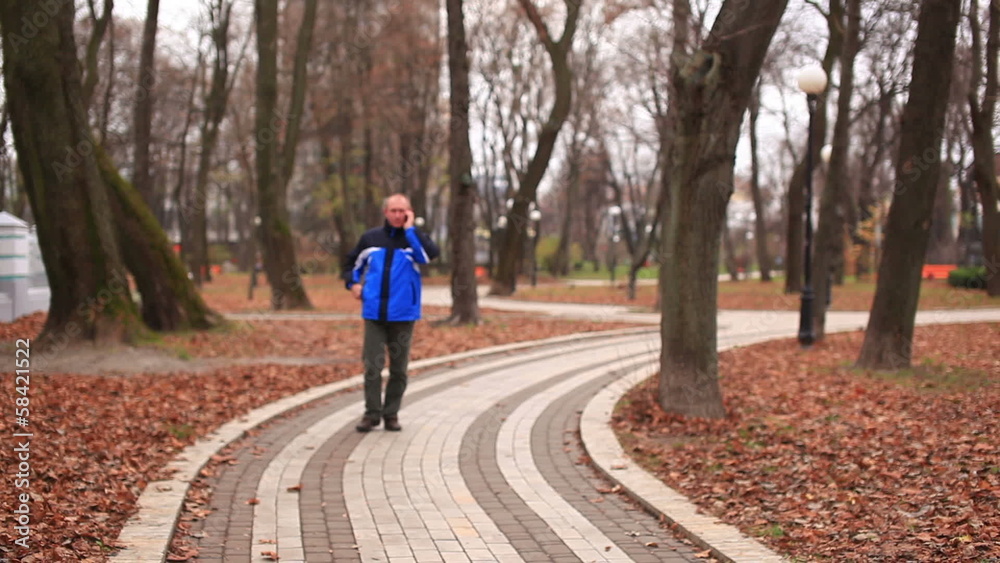 Adult man talking on mobile in autumn park Adult man talking on mobile in autumn park