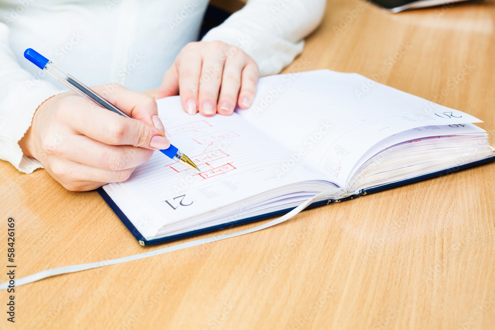 Business Woman Writing with pen in notepad Business Woman Writing with pen in notepad