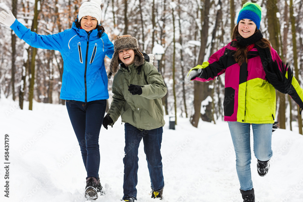 Active family - mother and kids running outdoor in winter park