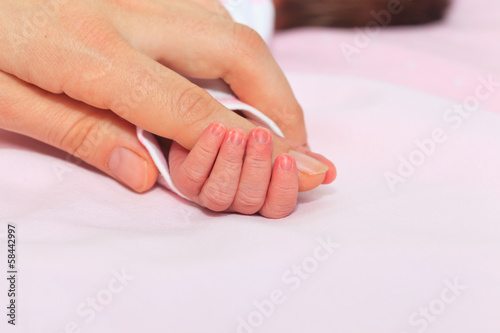 Newborn baby is held by the hand the parent