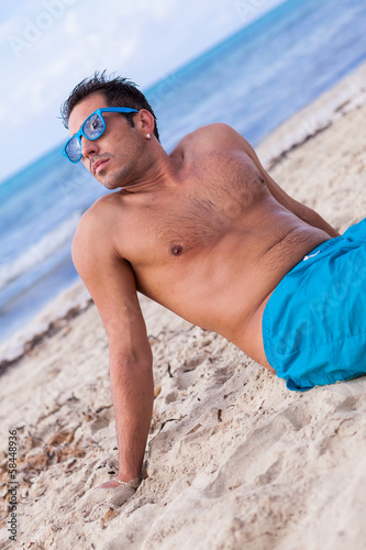 sportlicher junger mann in badehose am strand im urlaub