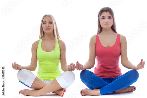 Pair of pretty young girls meditates in studio