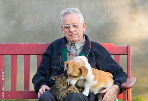 Senior man wirh dog and cat on his lap on bench
