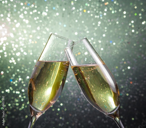 Fényképezés champagne flutes with gold bubbles on green light bokeh