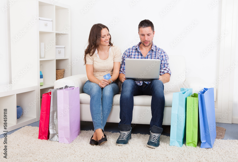 Young Couple Sitting On Couch Shopping Online Young Couple Sitting On Couch Shopping Online