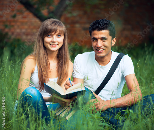 Two students guy and girl studying in park on grass with book © vladstar