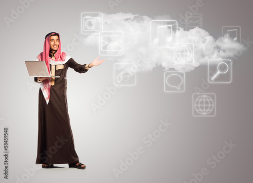 Young smiling arab with laptop shows virtual  icons of the cloud