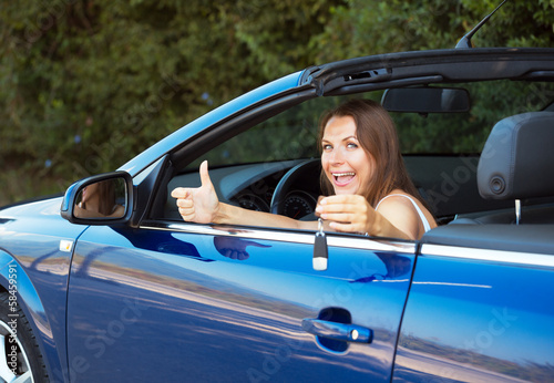 Smiling caucasian woman showing key in a cabriolet