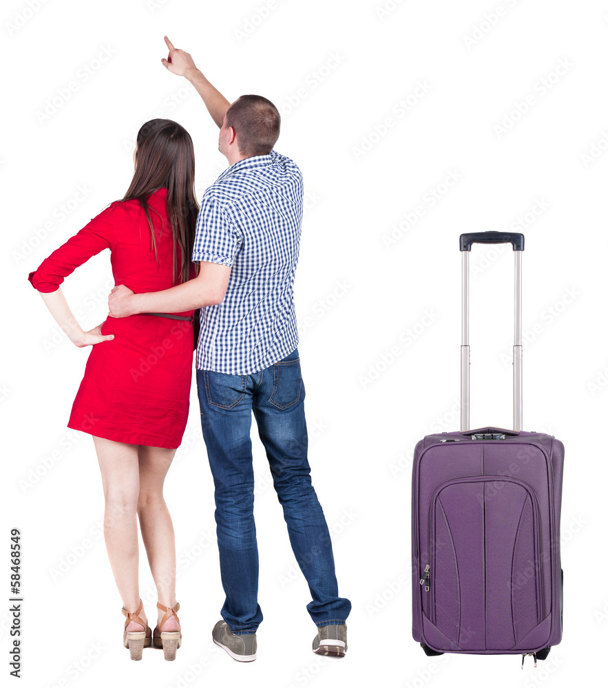 young couple traveling with suitcas and pointing at wal Back vie young couple traveling with suitcas and pointing at wal Back vie