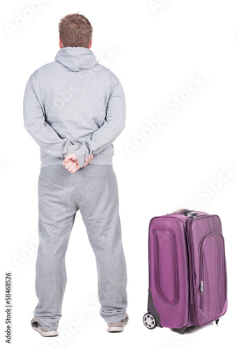 Back view of young man traveling with suitcas.