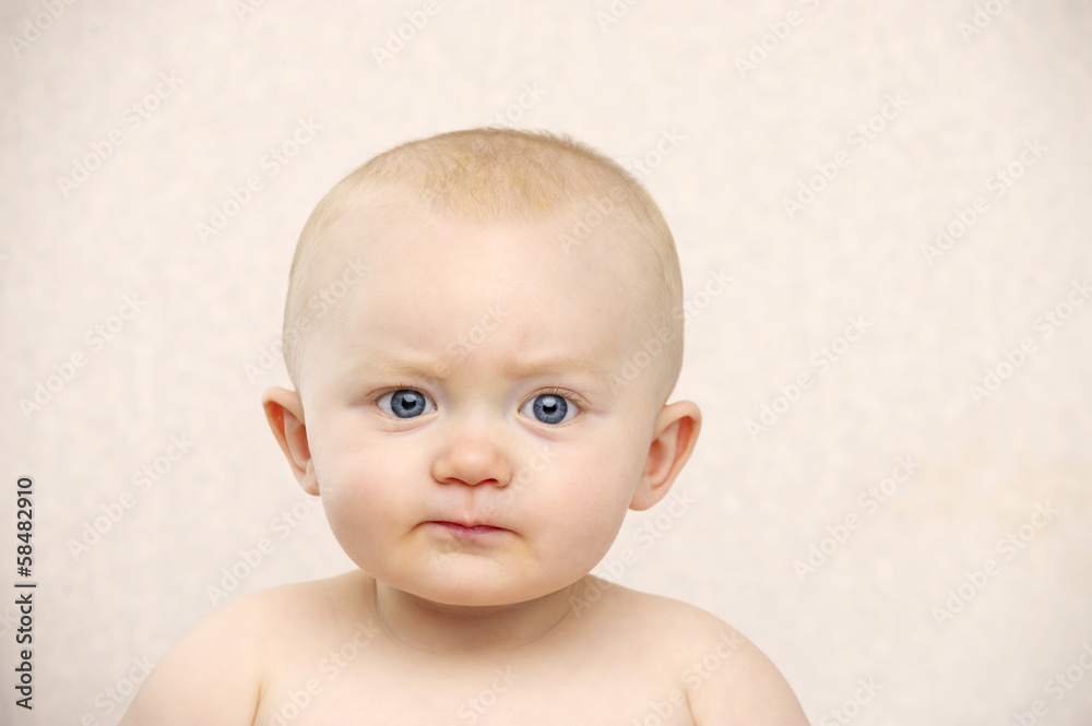 Baby looking at the camera on a peach background