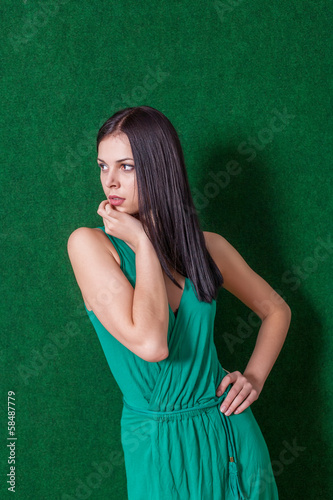 brunette in green dress against wall