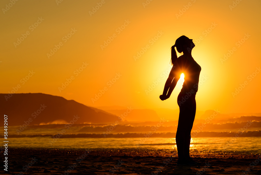 Relaxing exercises on beach at sunset