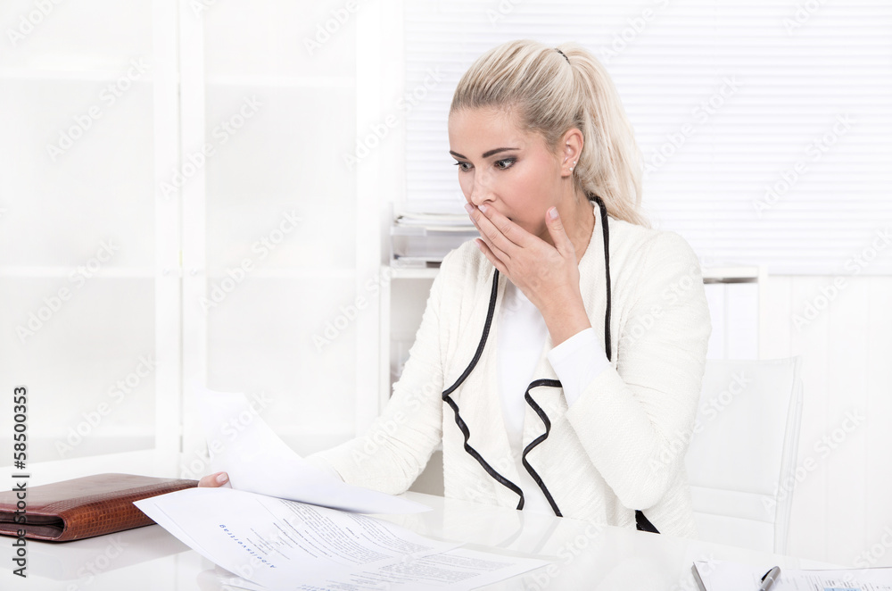Schockierte blonde junge Frau im Büro Schockierte blonde junge Frau im Büro