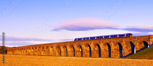 Fotografie Old masonry arched viaduct carrying a train