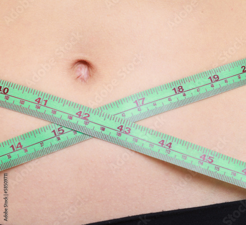 Weight loss. Green measuring tape on woman body