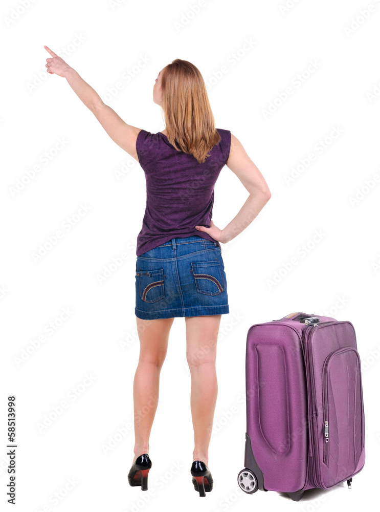 Beautiful young woman in dress traveling with suitcas and point Beautiful young woman in dress traveling with suitcas and point