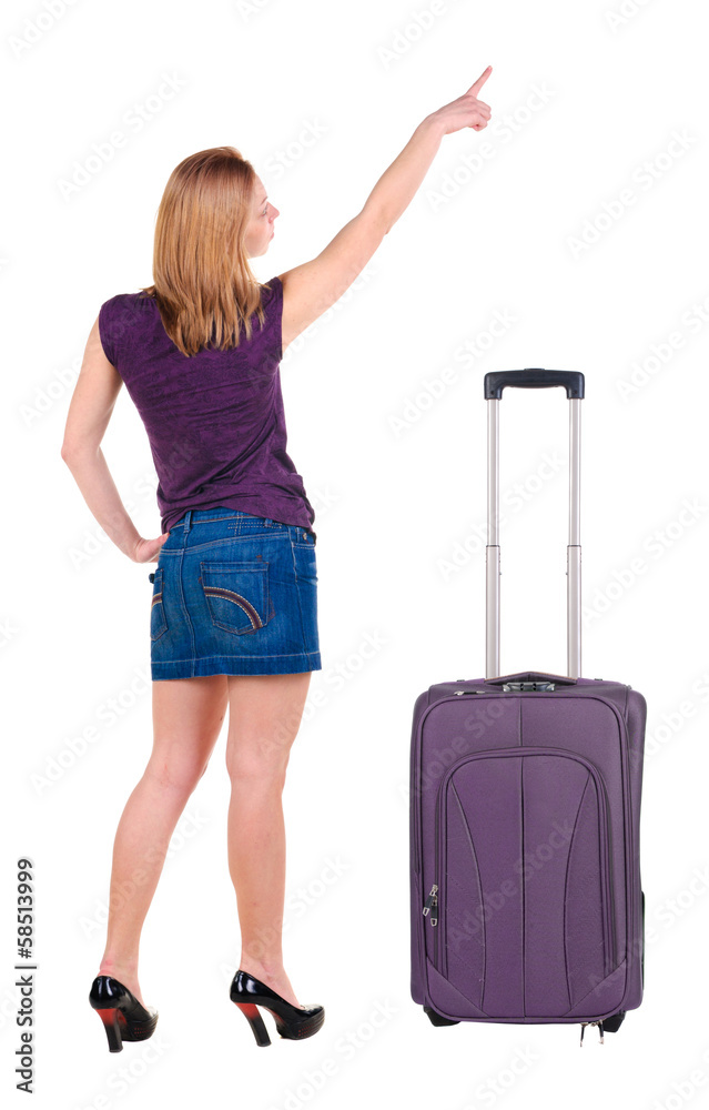Beautiful young woman in dress traveling with suitcas and point Beautiful young woman in dress traveling with suitcas and point