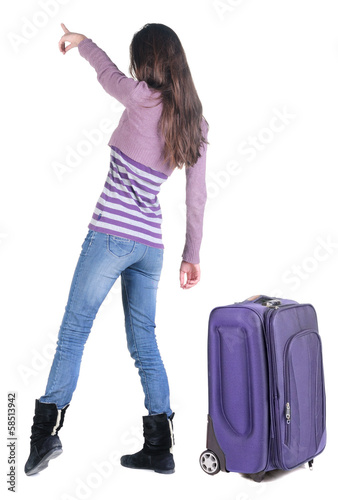 Beautiful young woman traveling with suitcas and pointing at wa