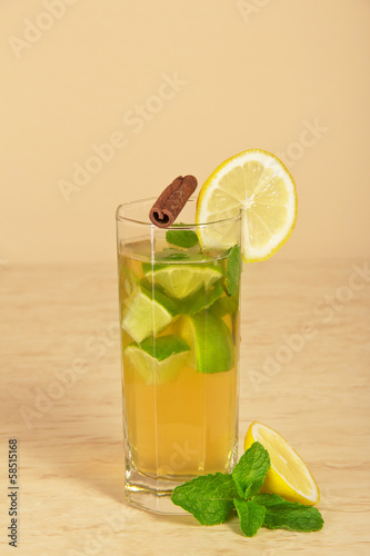 Drink with a lemon slice, stick of cinnamon and mint
