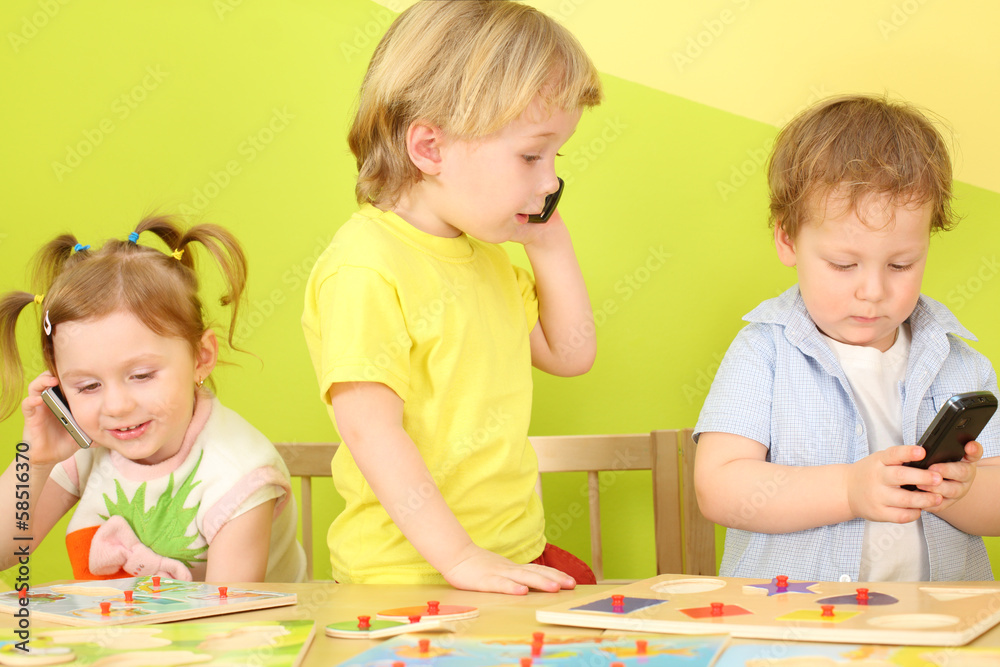 Fototapeta premium Three children with the phones in hand