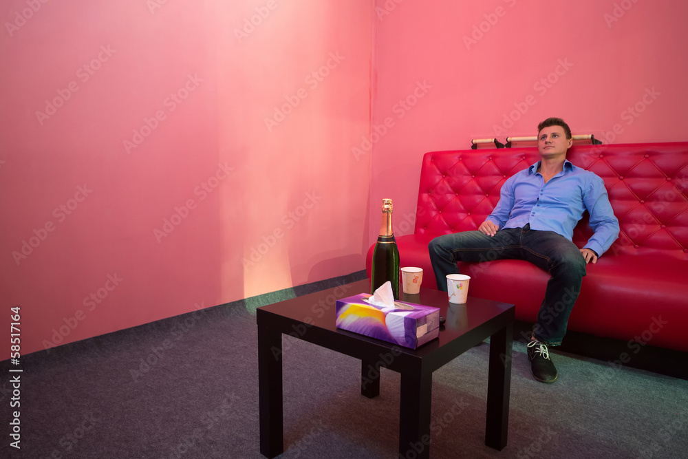 Fototapeta premium A man is sitting on a red couch in a room