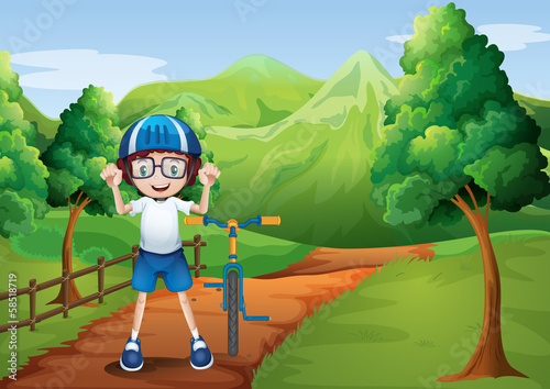 A happy child with a bike at the pathway with a wooden fence