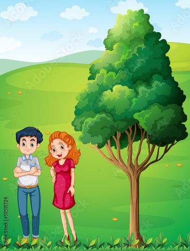 A mother and a father near the big tree at the hilltop