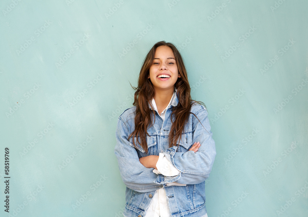 Young woman laughing with arms crossed against blue background Young woman laughing with arms crossed against blue background