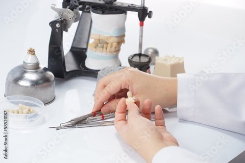 Dental technician working with articulator in dental laboratory