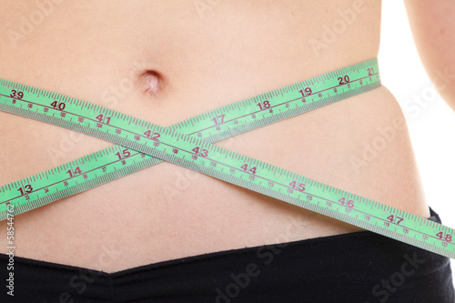 Weight loss. Green measuring tape on woman body